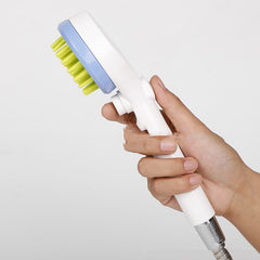 2-in-1 dog bath brush with shower head held in hand, featuring green rubber bristles and blue handle.